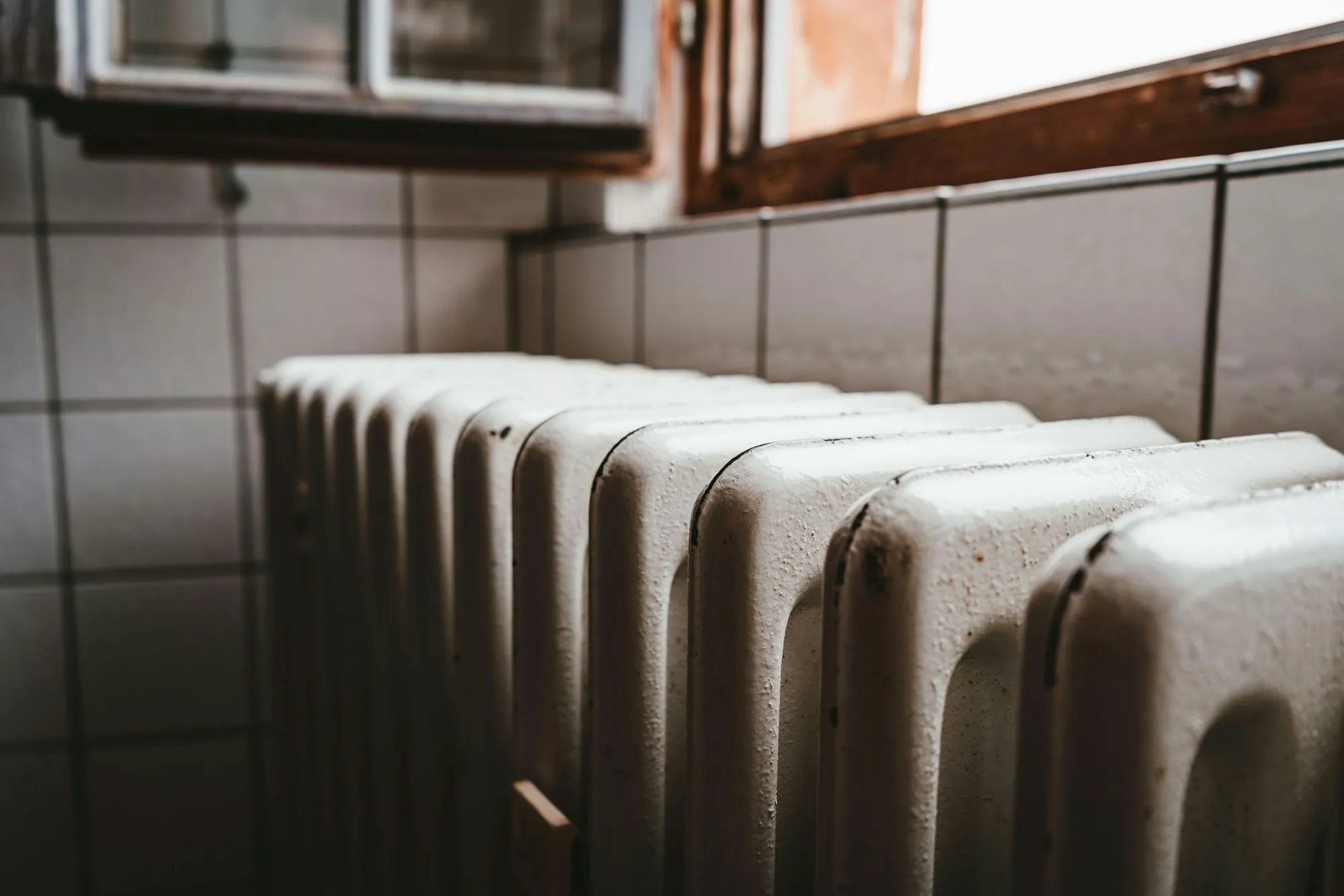 A painted cast-iron radiator under a wooden window