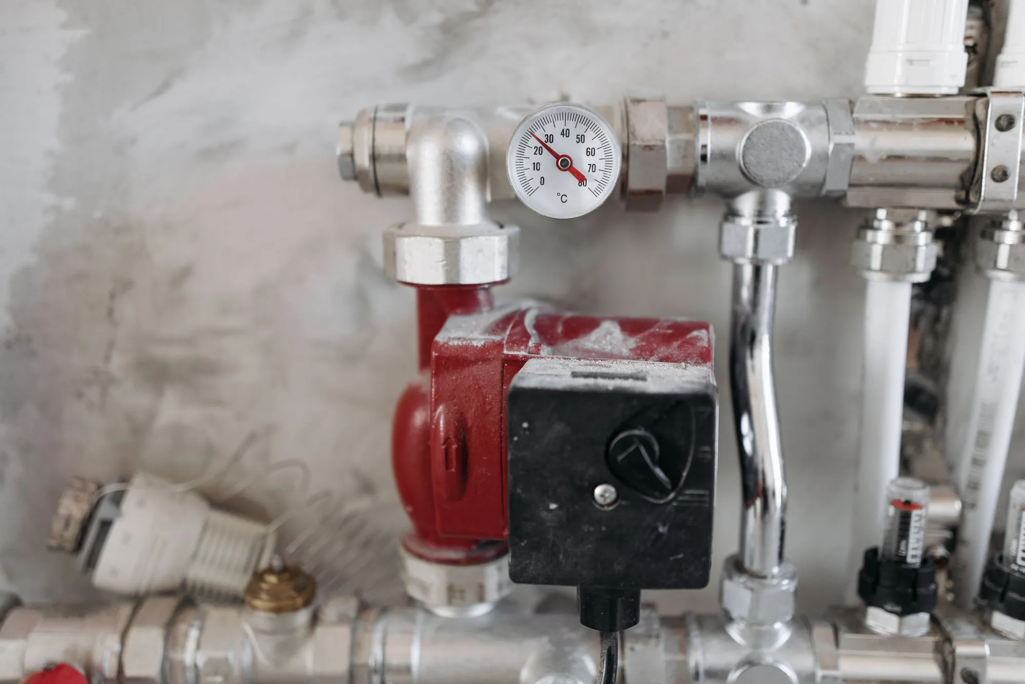 A red circulator pump and temperature gauge on chrome heating pipes
