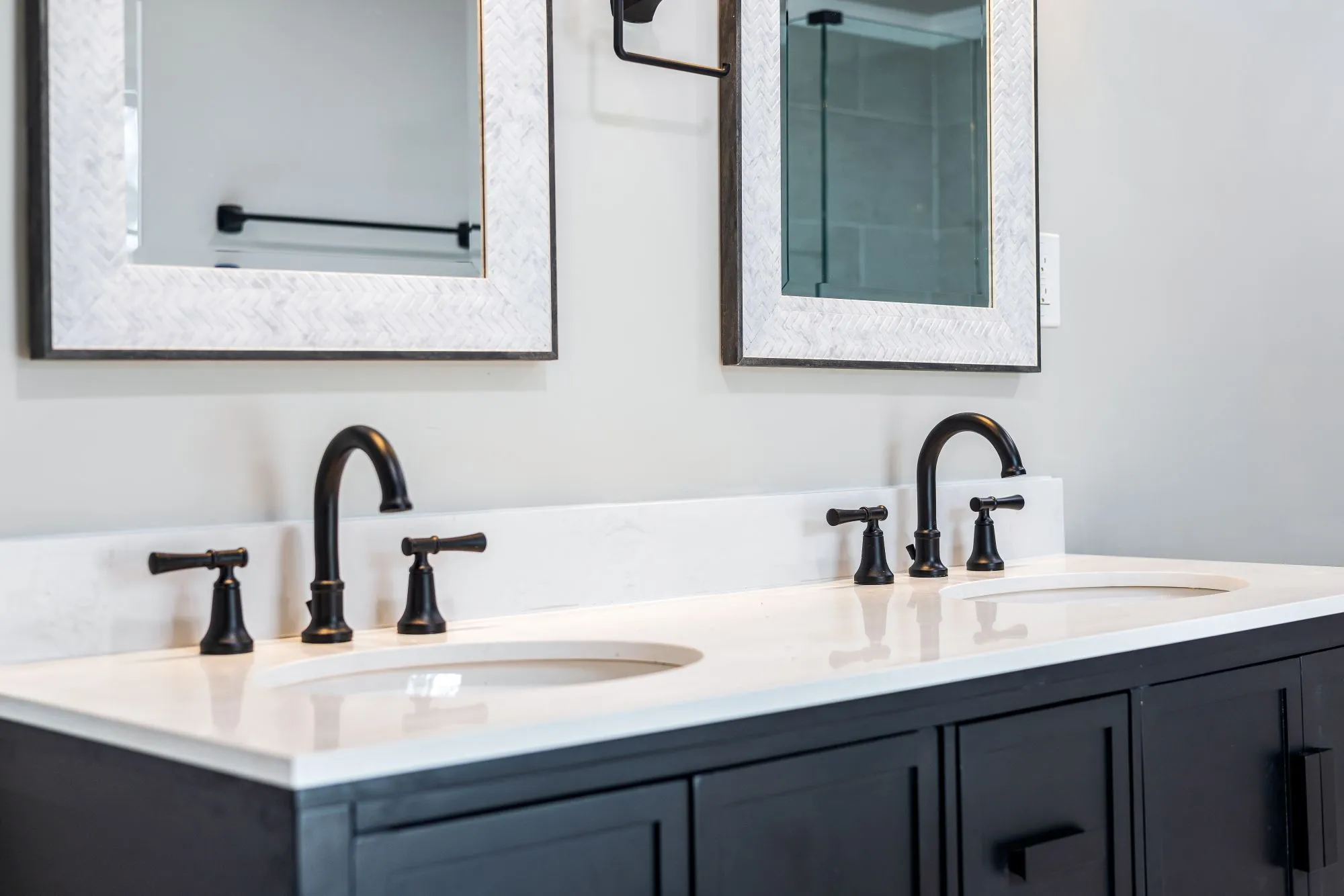 A navy double vanity with a white stone top and two matte black faucets