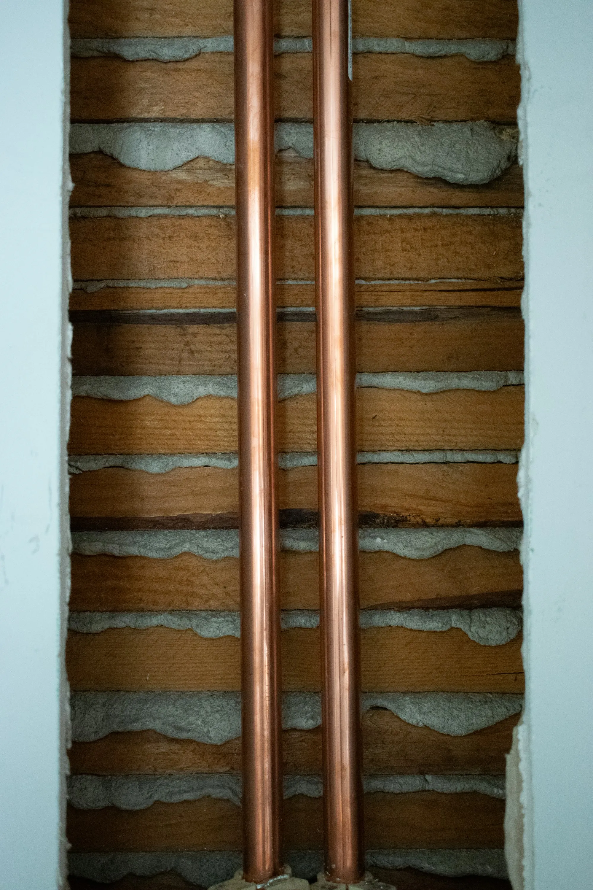 Two new copper supply lines running up through the same opened wall