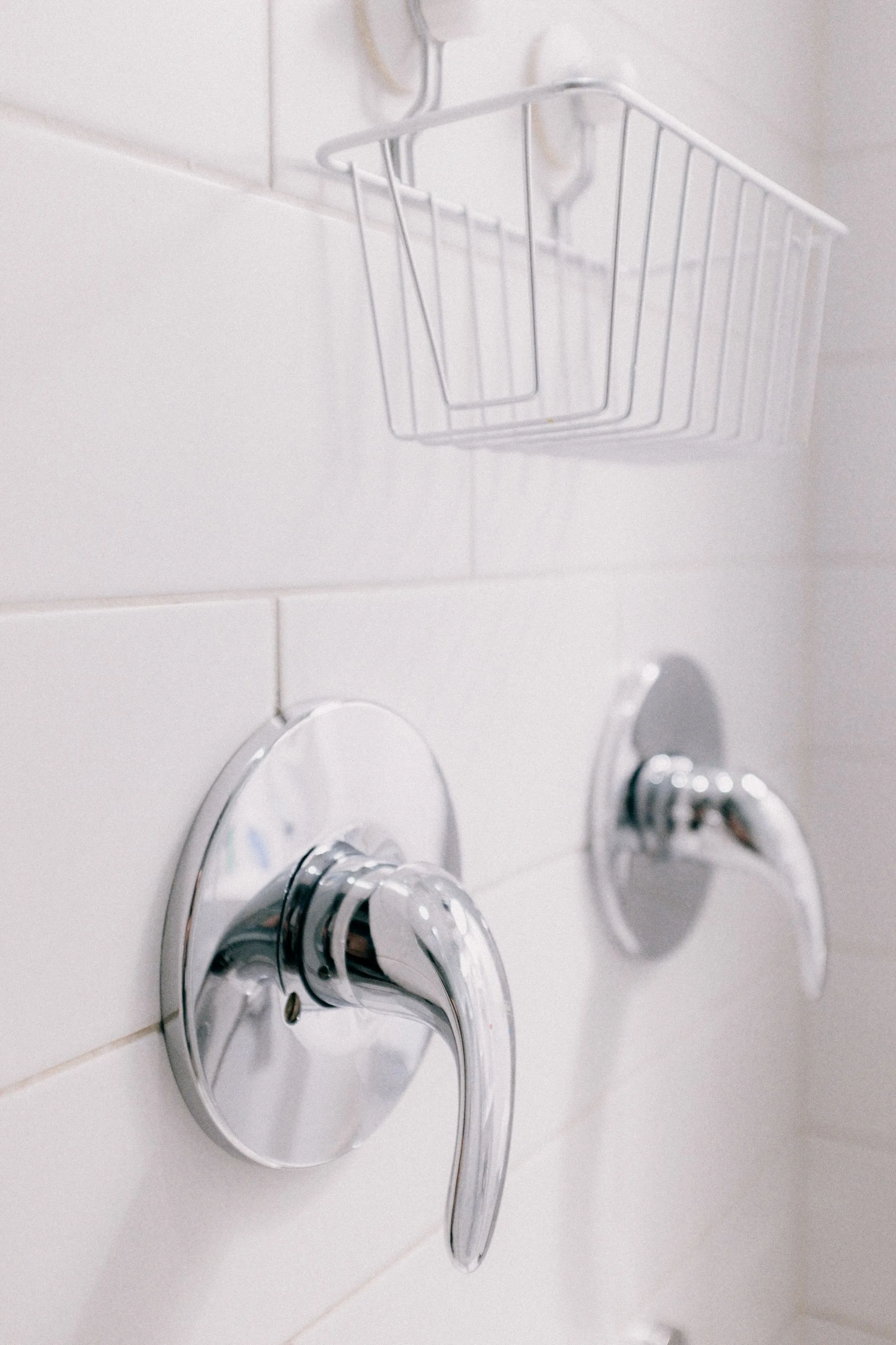 A new chrome shower valve handle and diverter on white tile